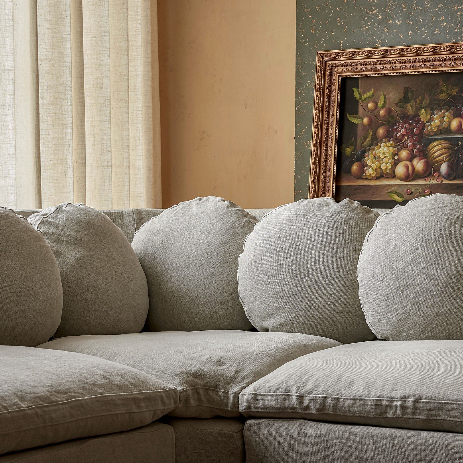 Close up view of the circular shaped pillows on the Olea Short Corner Sectional in Jasmine Rice, a light warm greige Medium Weight Linen