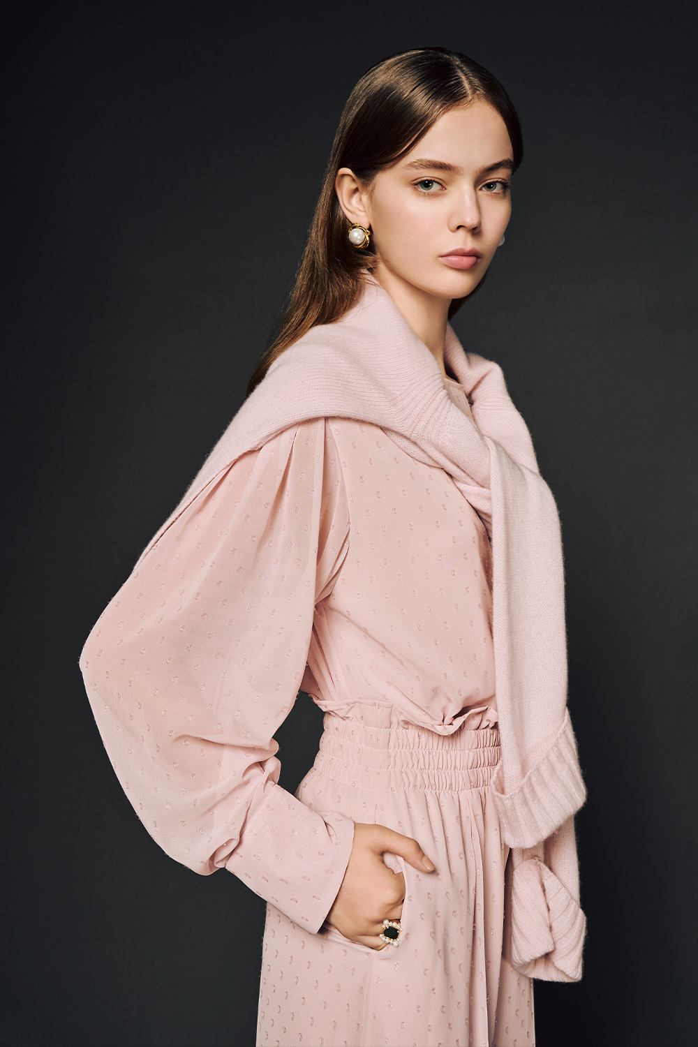 Model is wearing a matching pink dotted set with long pants, long sleeve top, and sweater tied around shoulders. 