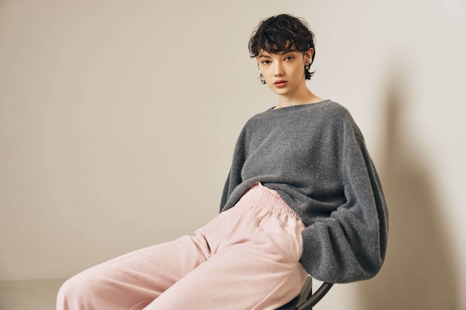 The model wears a grey sweater with light pink pants. 