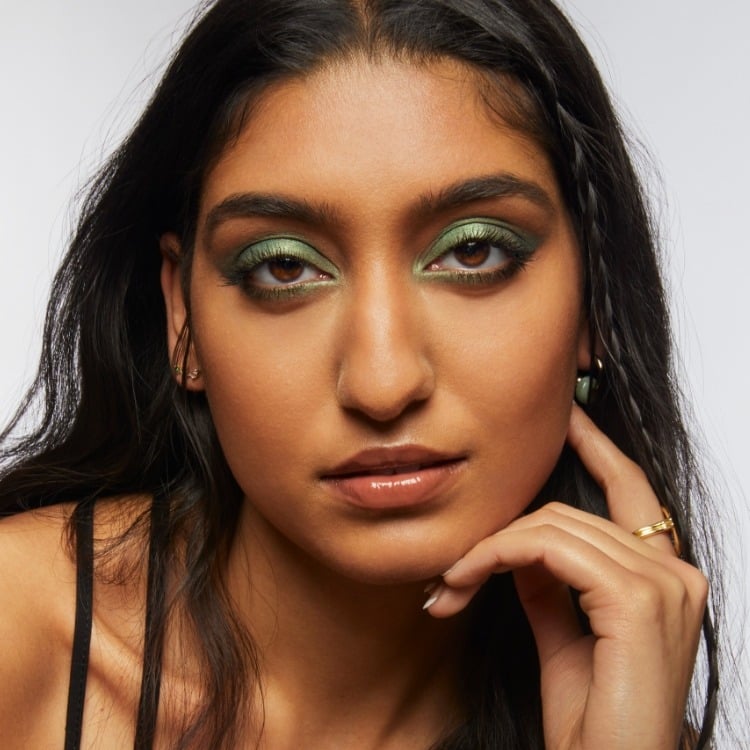 Portrait of Milk Makeup model Lizzy with smoky green eyeshadow on a white background
