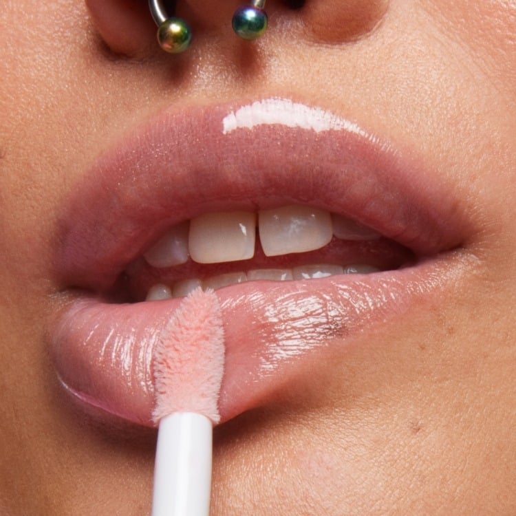 Close-up shot of model with a fair-medium skin tone applying Milk Makeup Odyssey Lip Oil Gloss in Soul Search