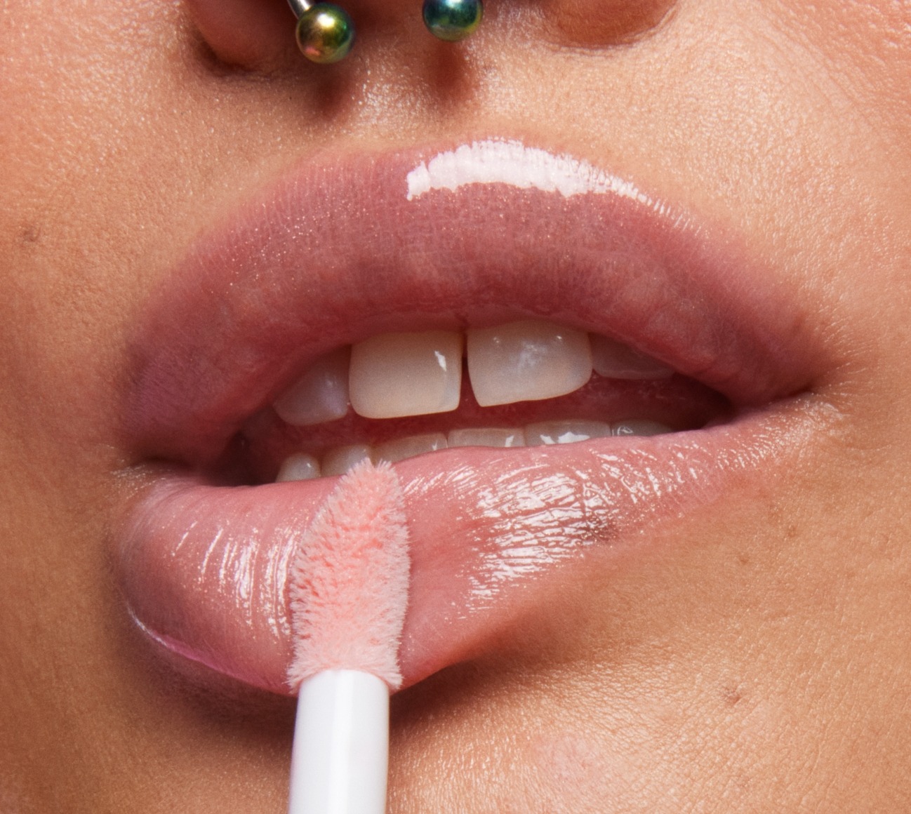 Close-up shot of model with a fair-medium skin tone applying Milk Makeup Odyssey Lip Oil Gloss in Soul Search