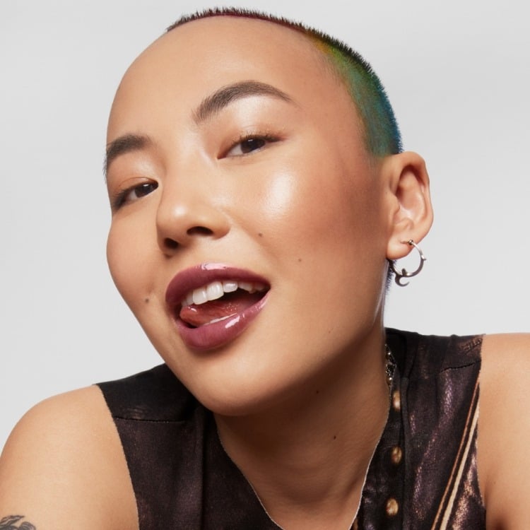 Model wears Milk Makeup Odyssey Lip Oil Gloss in Voyage on a white background