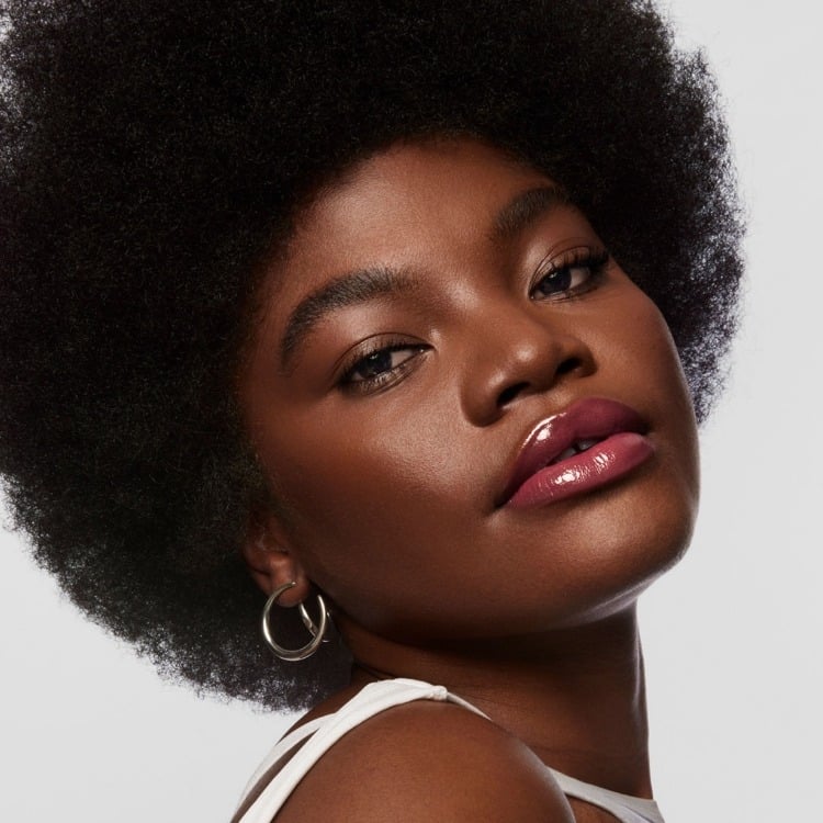 Model wears Milk Makeup Odyssey Lip Oil Gloss in Trek on a white background