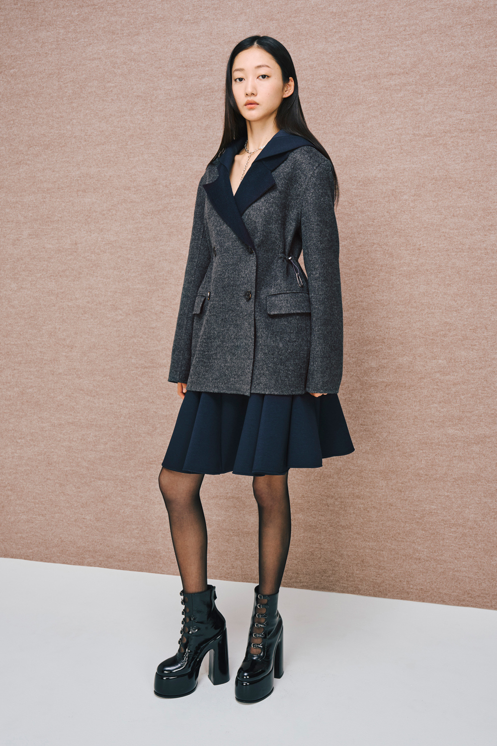 Model is wearing a navy skirt and a gray coat.
