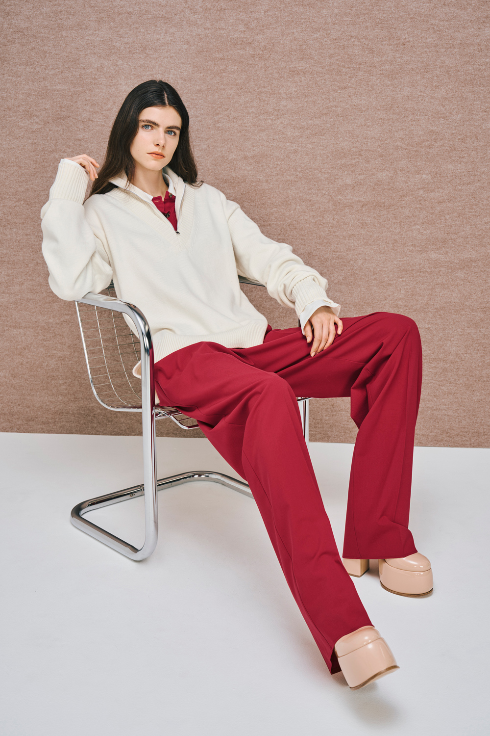 Model is wearing red pants with a white cardigan over a red top.