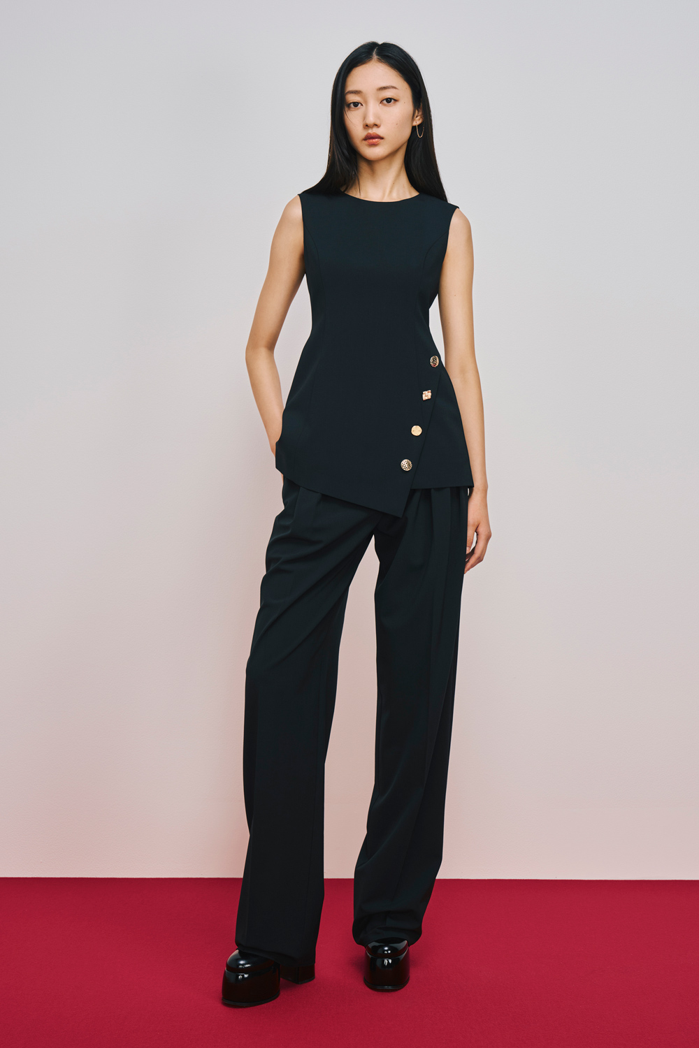 Model is wearing black pants with a black sleeveless top.