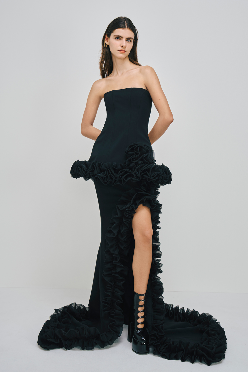 Model is wearing a black skirt with ruffle detailing and a matching top.