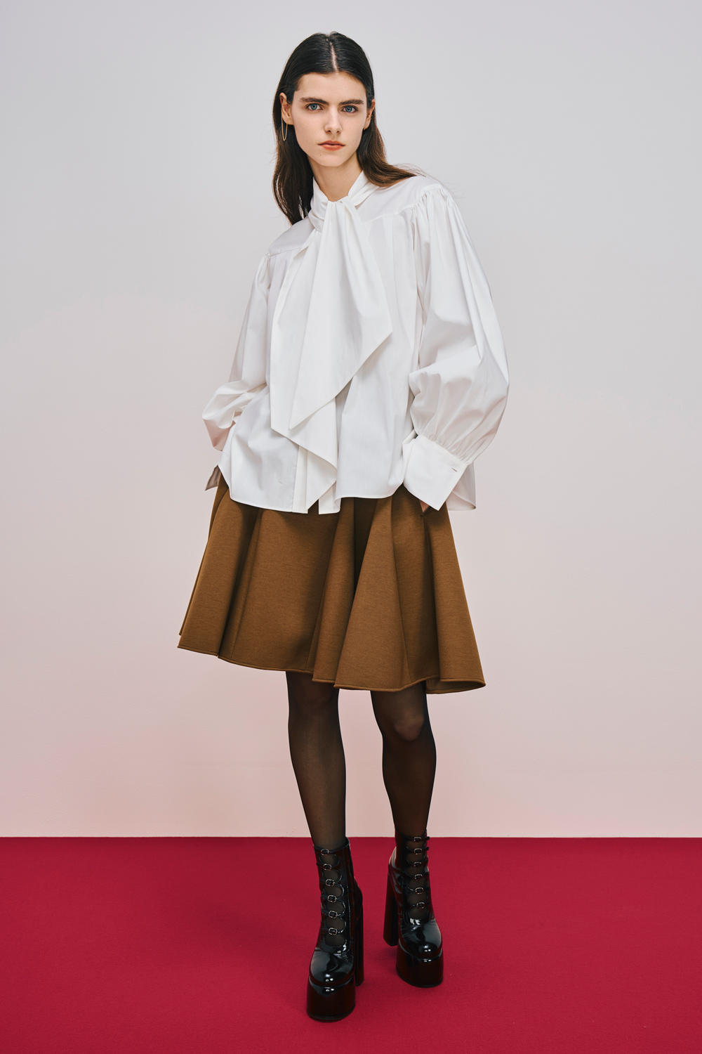 Model is wearing a brown skirt with a white top.