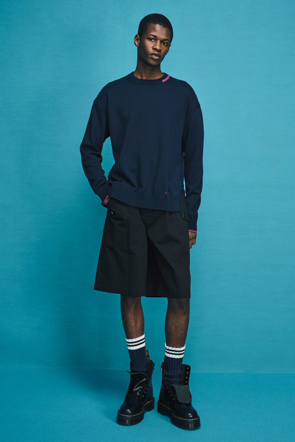 Model is wearing a navy sweater and black shorts.