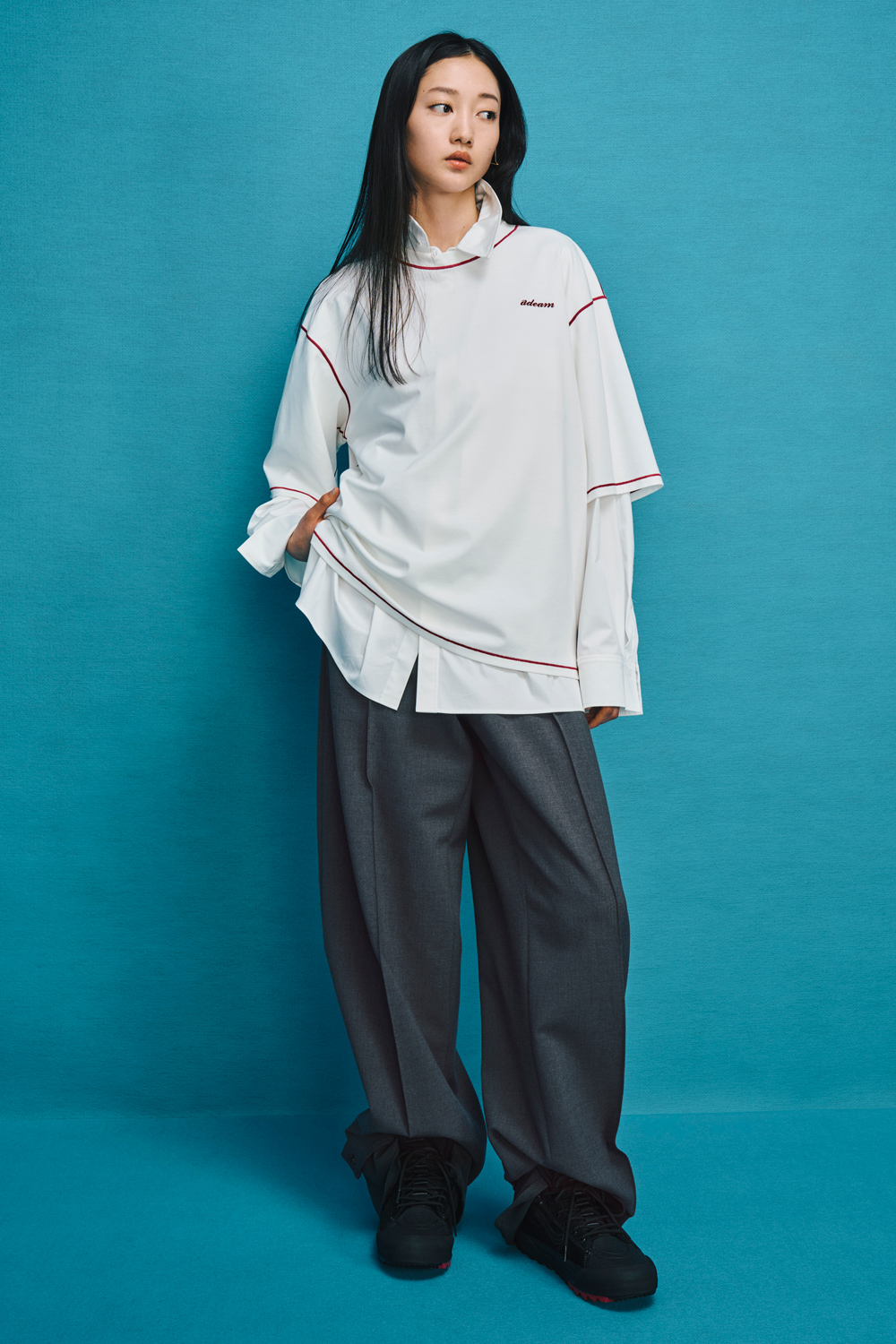 Model is wearing gray pants with a white shirt over a white t-shirt.