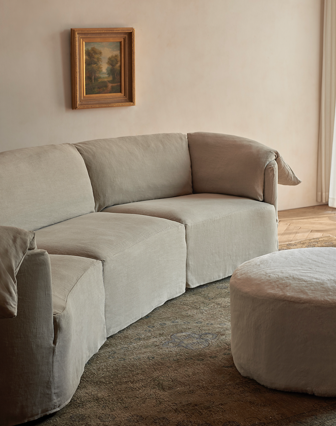 Loula Chaise Sectional in Light Weight Linen Oat Flour, placed on top of a rug