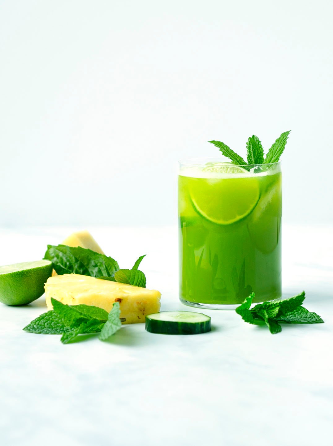 Pineapple Mint Basil Refresher green juice in a glass with lemon and mint