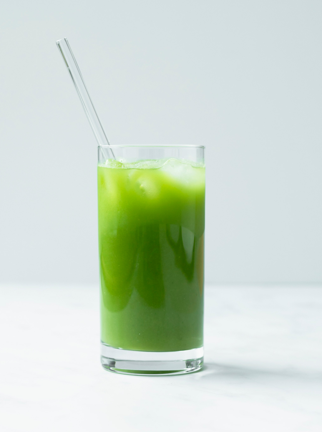 a glass of nourishing little green juice with a straw