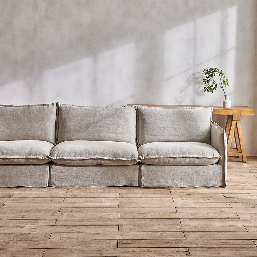 Neva Sectional Sofa in Medium Weight Linen Jasmine Rice placed by a window in a sunlit room