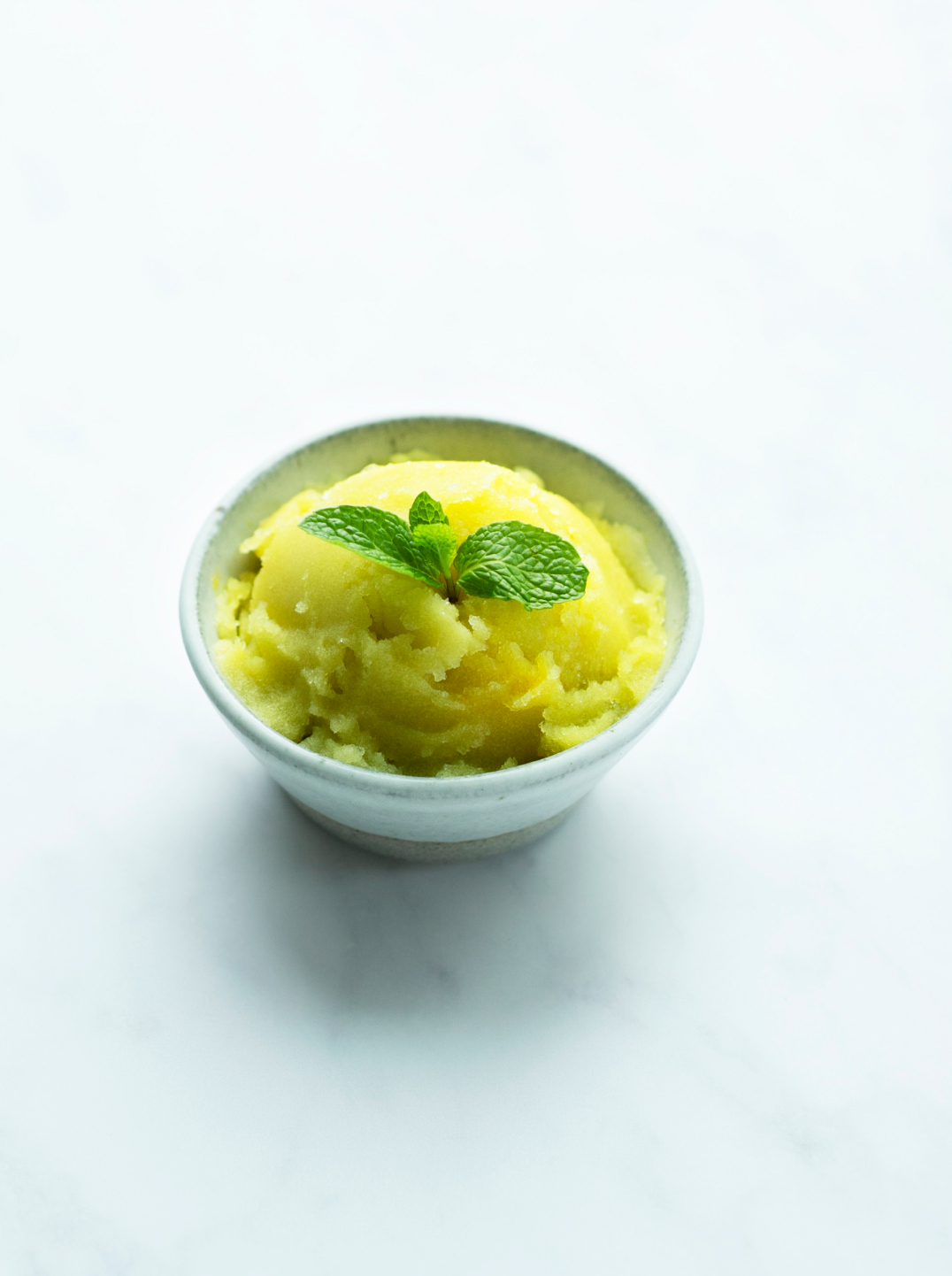 a bowl of ginger mint apple sorbet topped with a sprig of mint