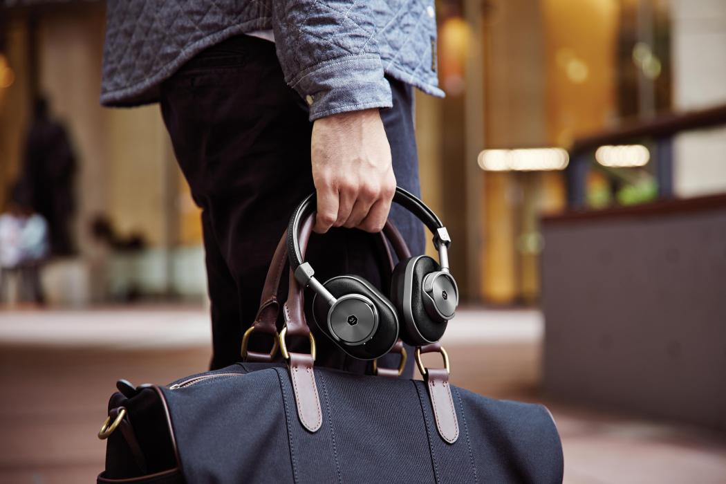 Lifestyle image of man holding bag and Master and Dynamic headphones