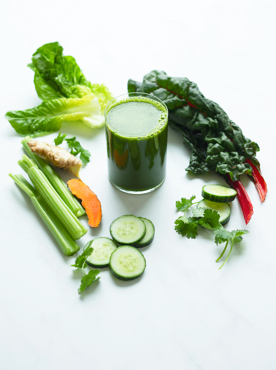 A glass of strong green juice with ingredients