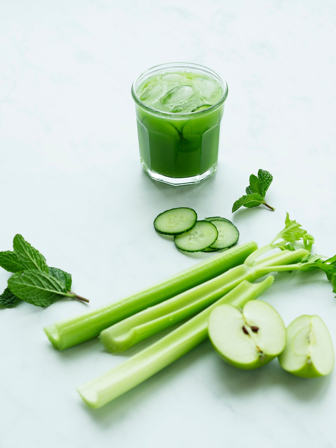 A glass of green juice with ingredients