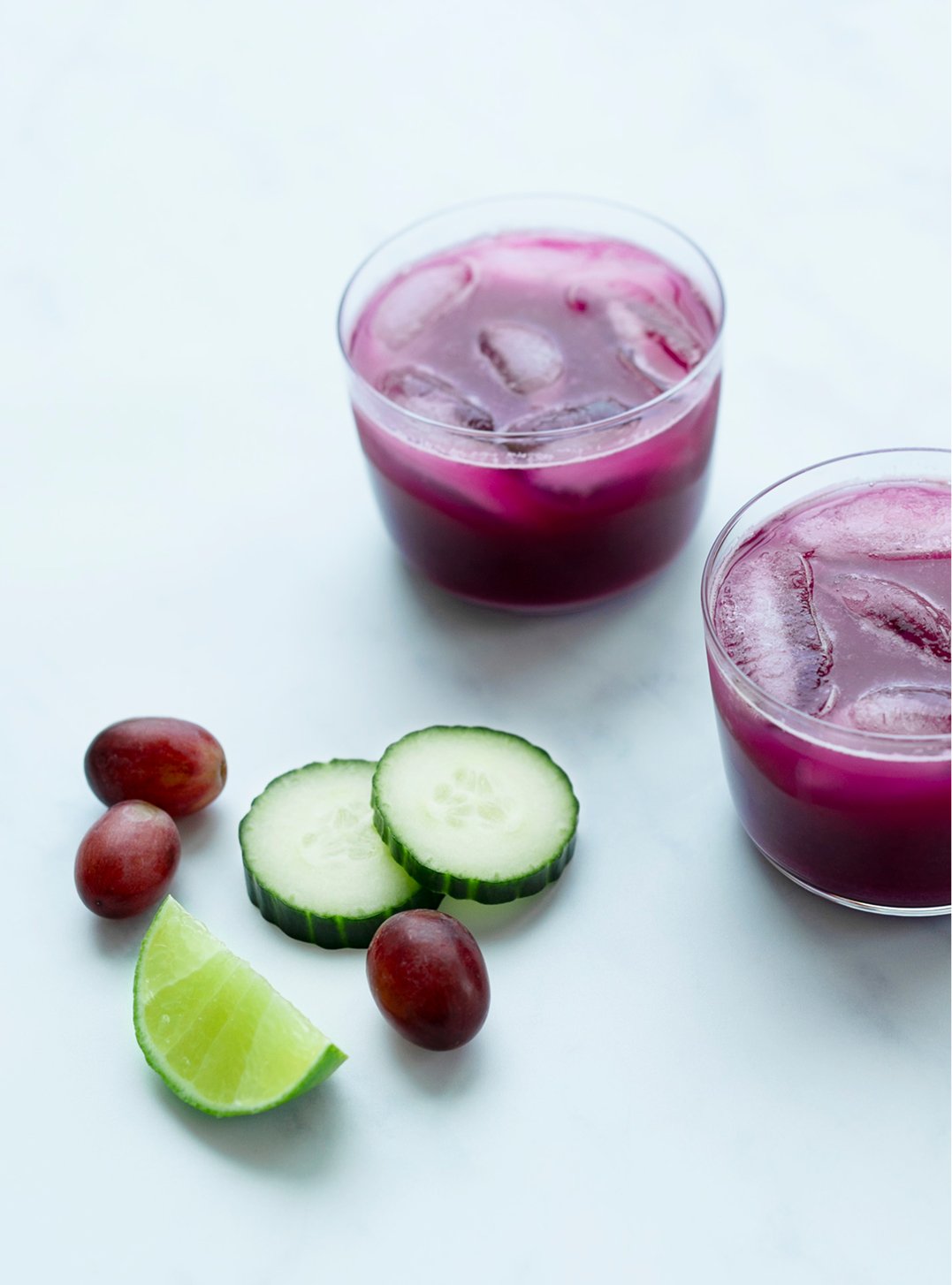 two glasses of deep red juice over ice with ingredients