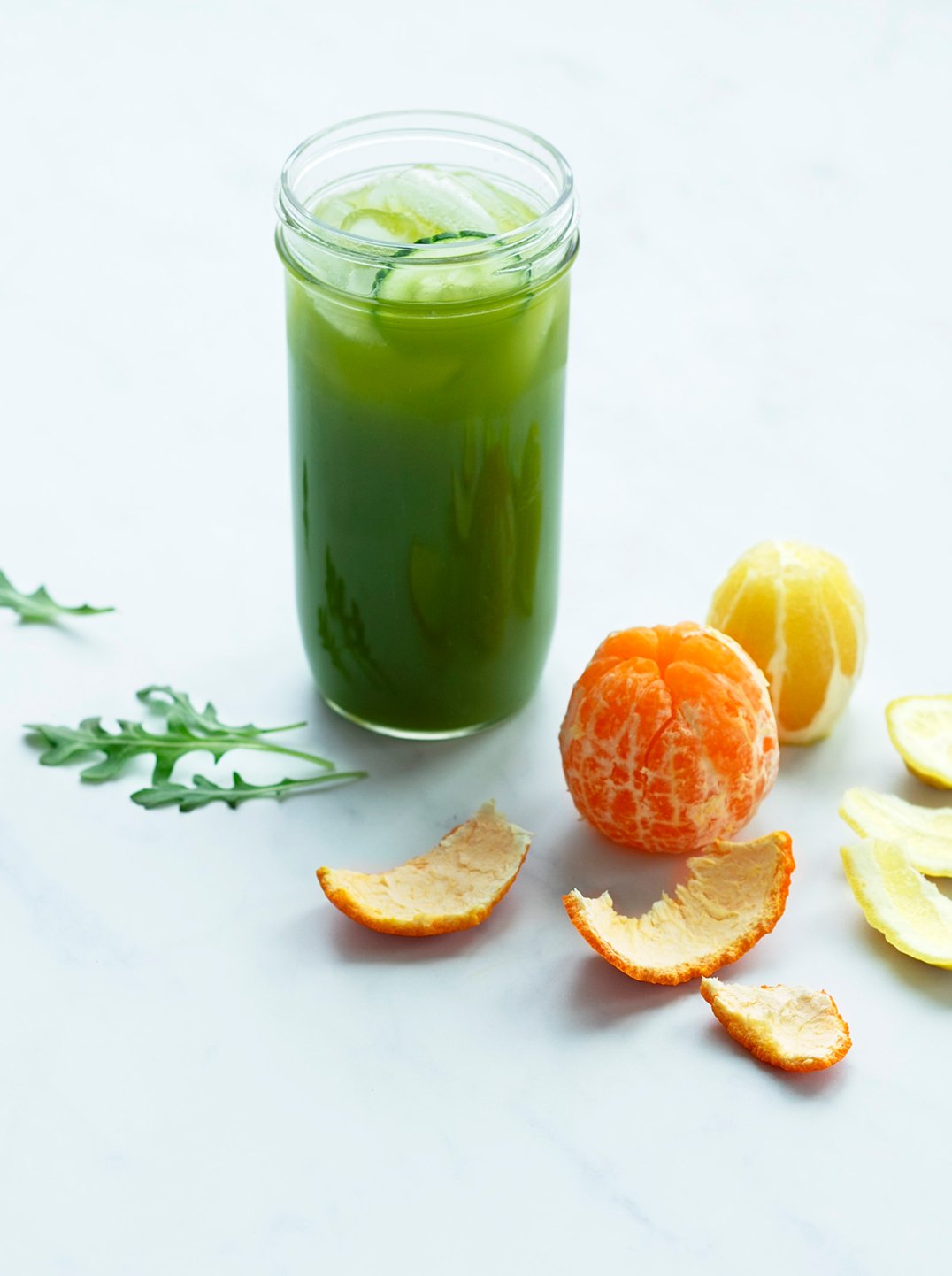 a glass jar filled with cucumber enhancer green juice with a peeled nectarine and lemon