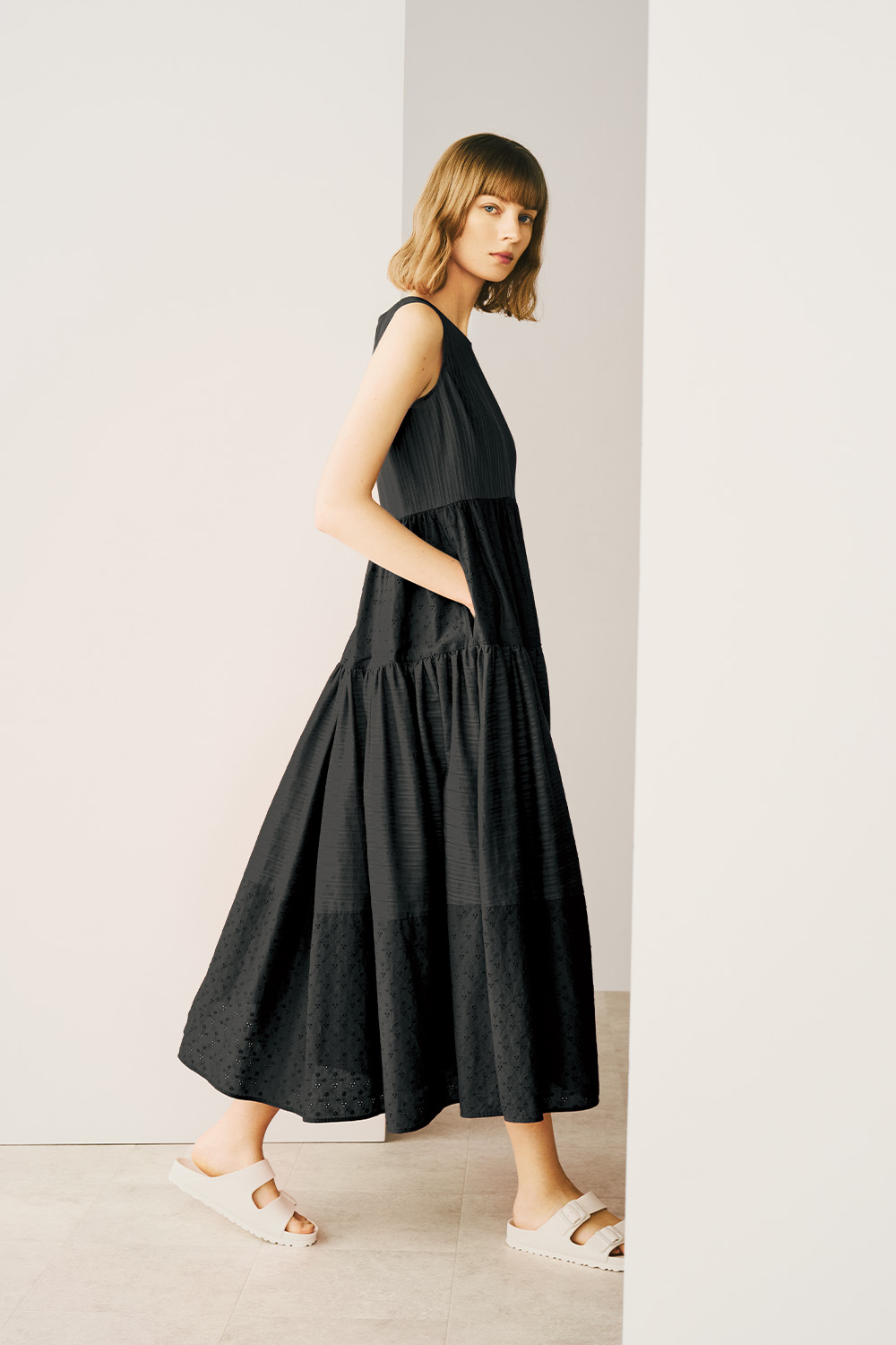 A model is wearing a black dress featuring a stylish tiered skirt