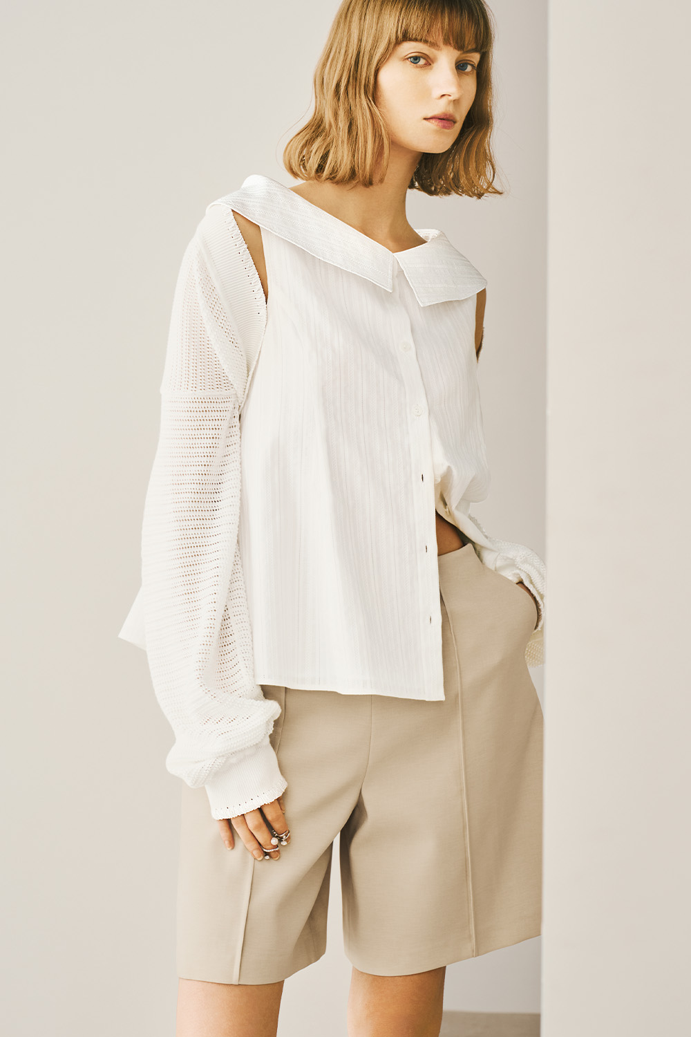 A model is wearing a white shirt and tan shorts