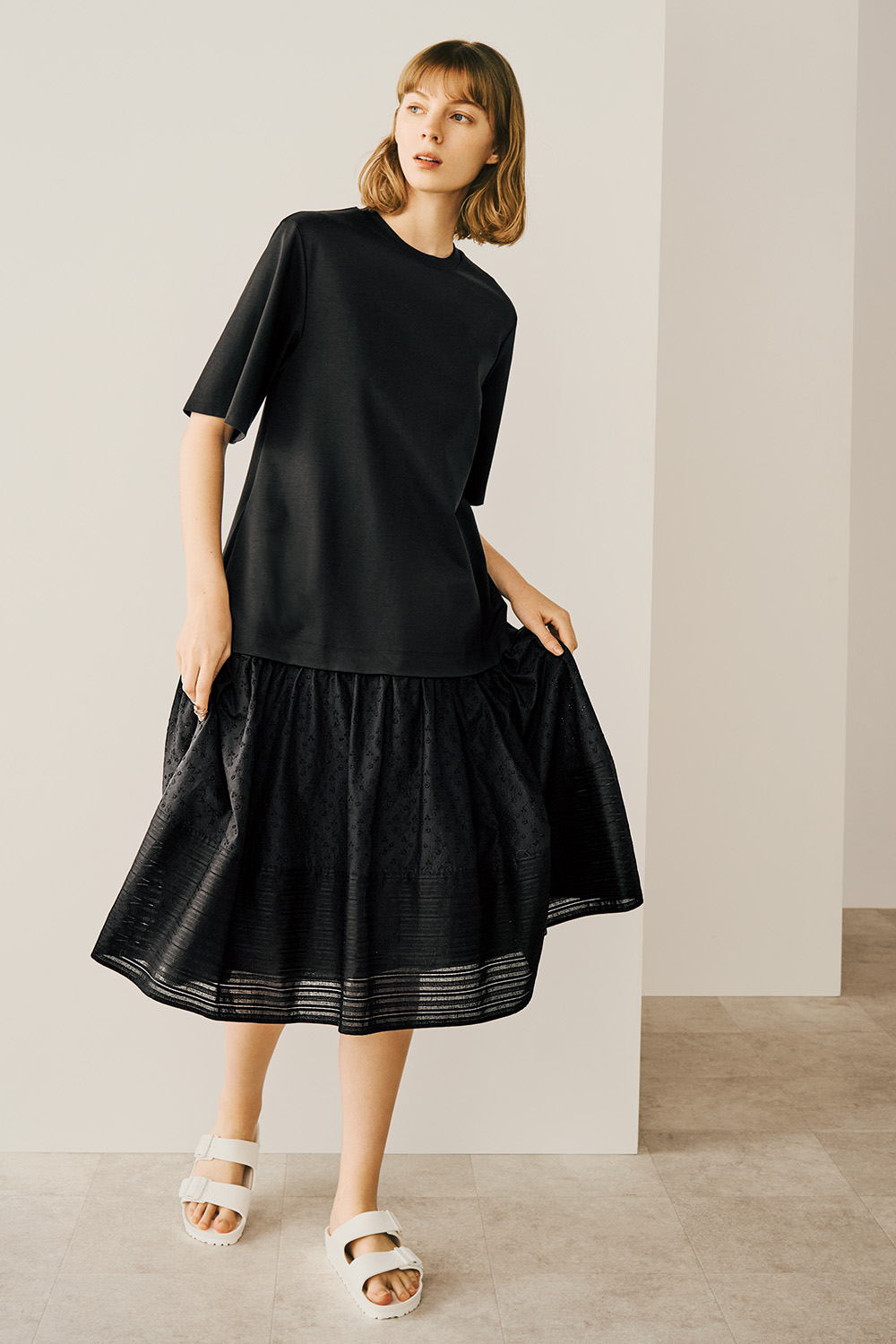 A model is wearing a black dress featuring a stylish ruffled hem