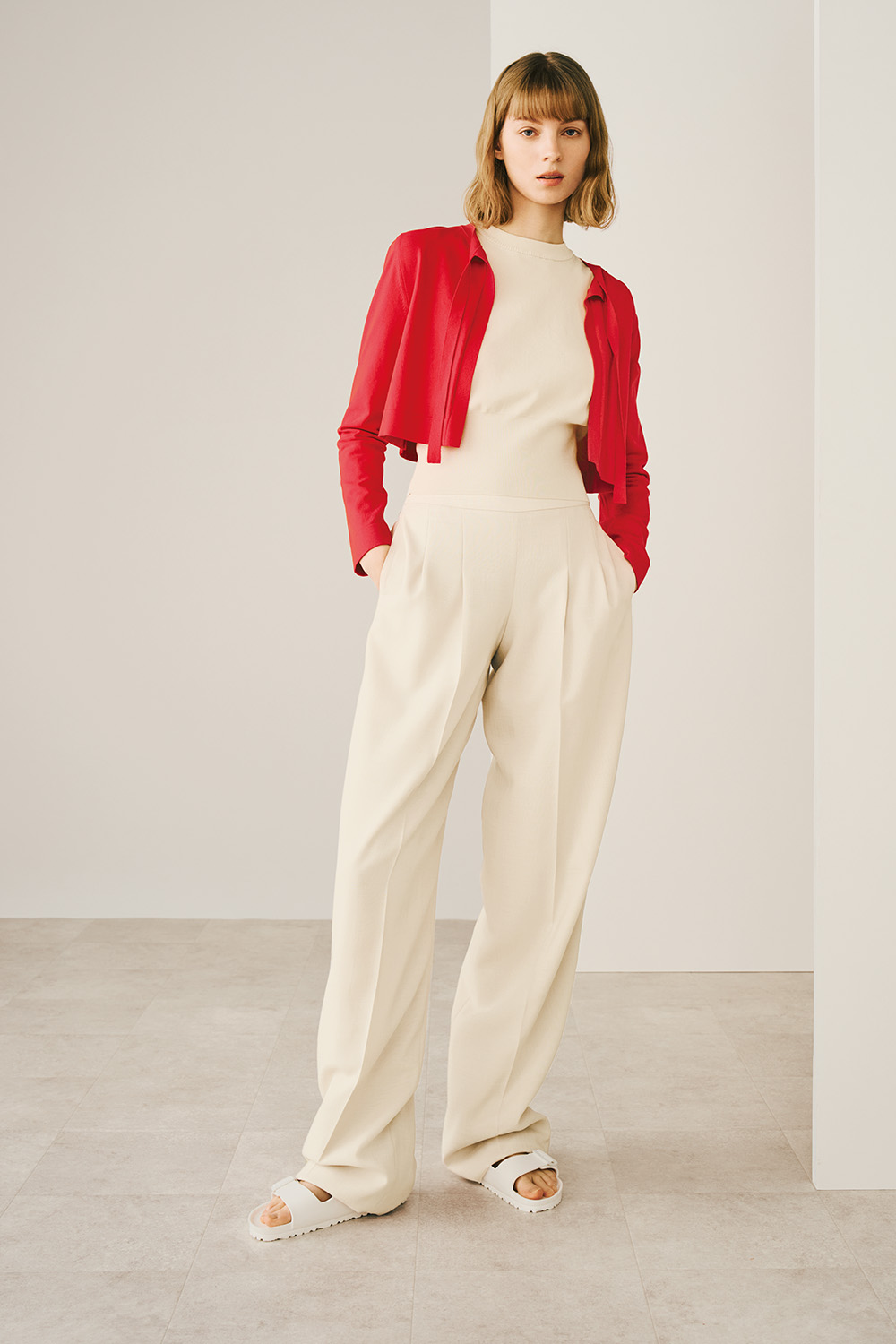 A woman is wearing a red jacket and white wide pants