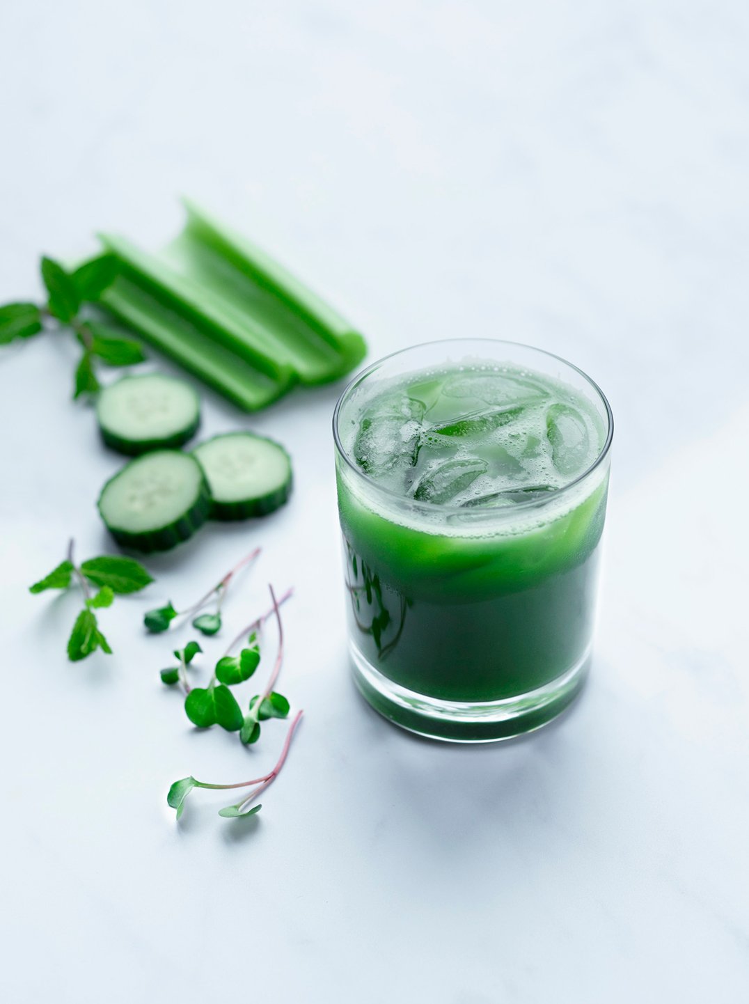 a glass of pure green reset with ice surrounded by ingredients