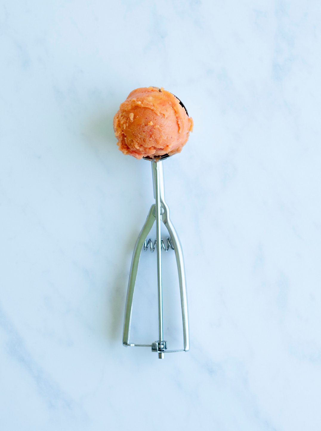 An ice cream scoop with a scoop of Hawaiian Sunset Sorbet