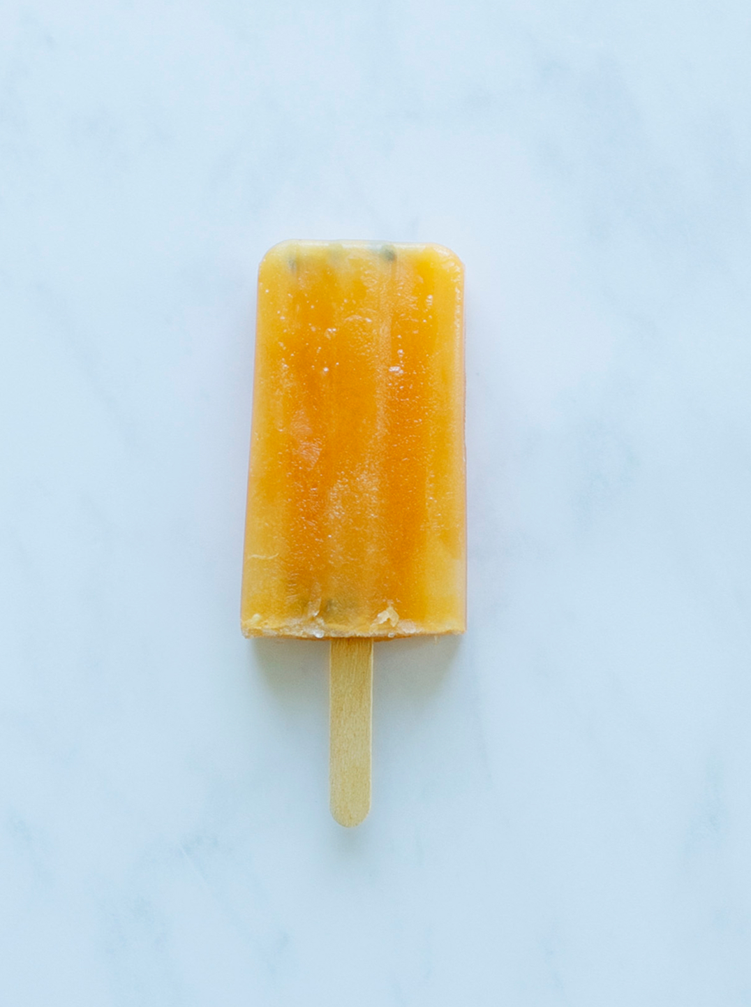  a single tropical glow popsicle on a maarble surface
