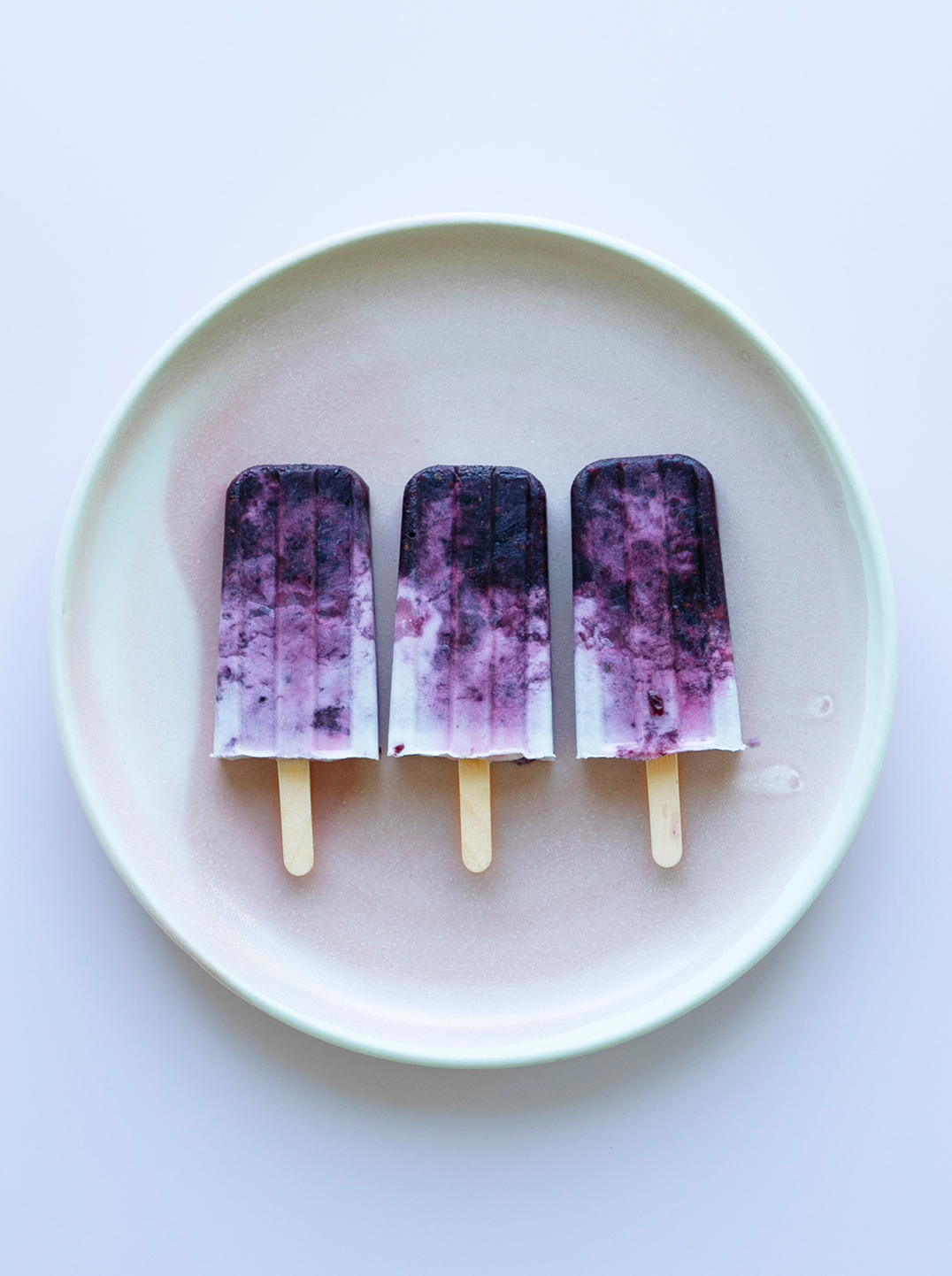 3 Blackberry Swirl Popsicles on a white plate
