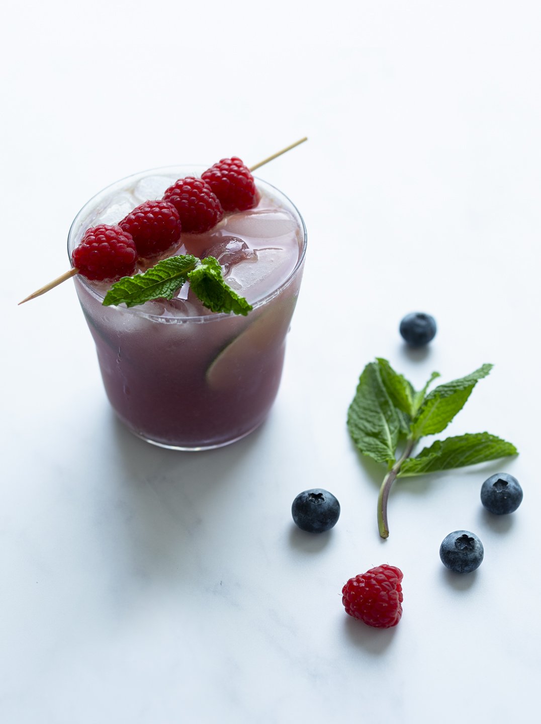 \a glass of Blueberry Mojito with raspberry garnish