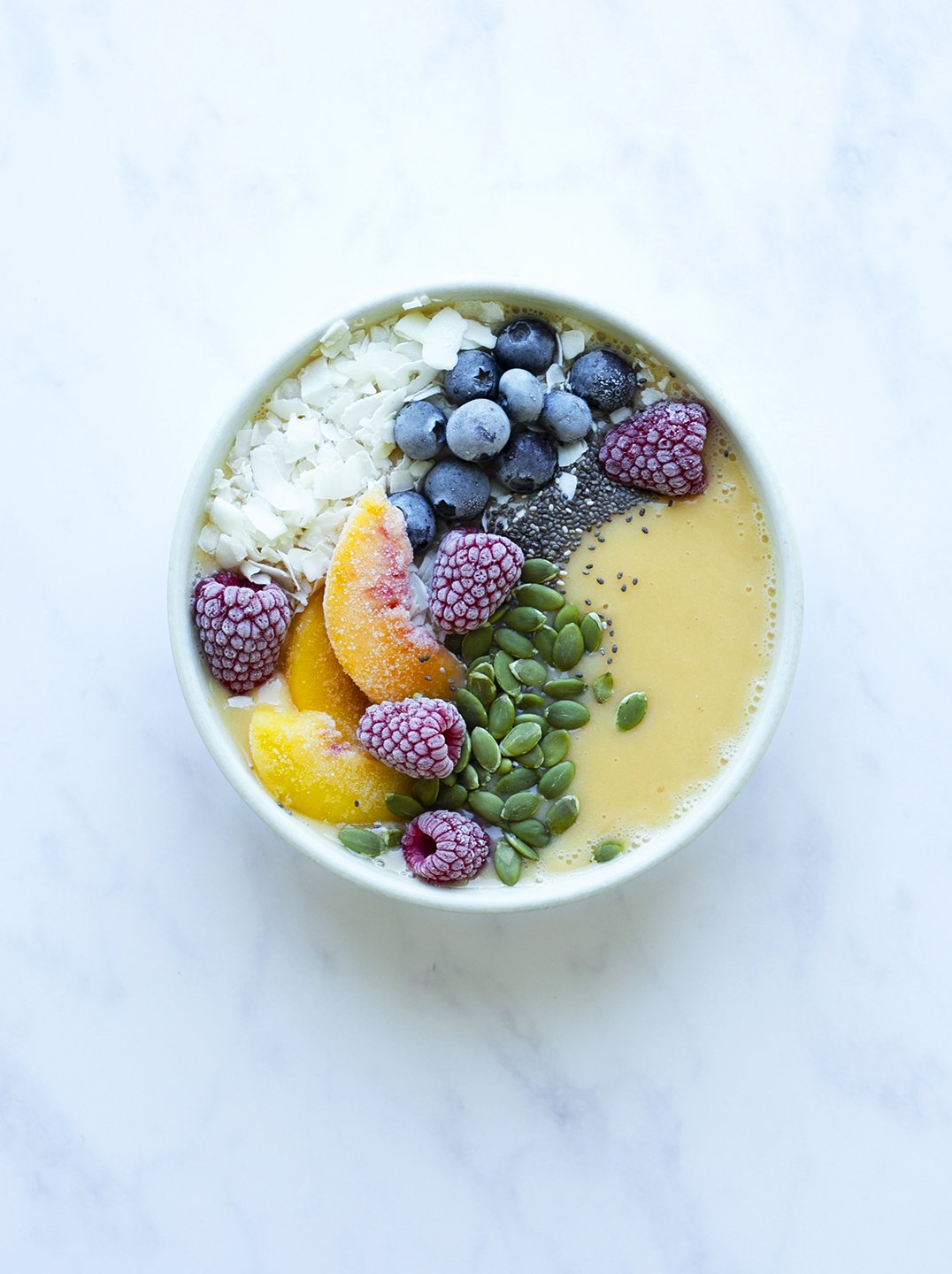 peach smoothie bow with berries and coconut flakes