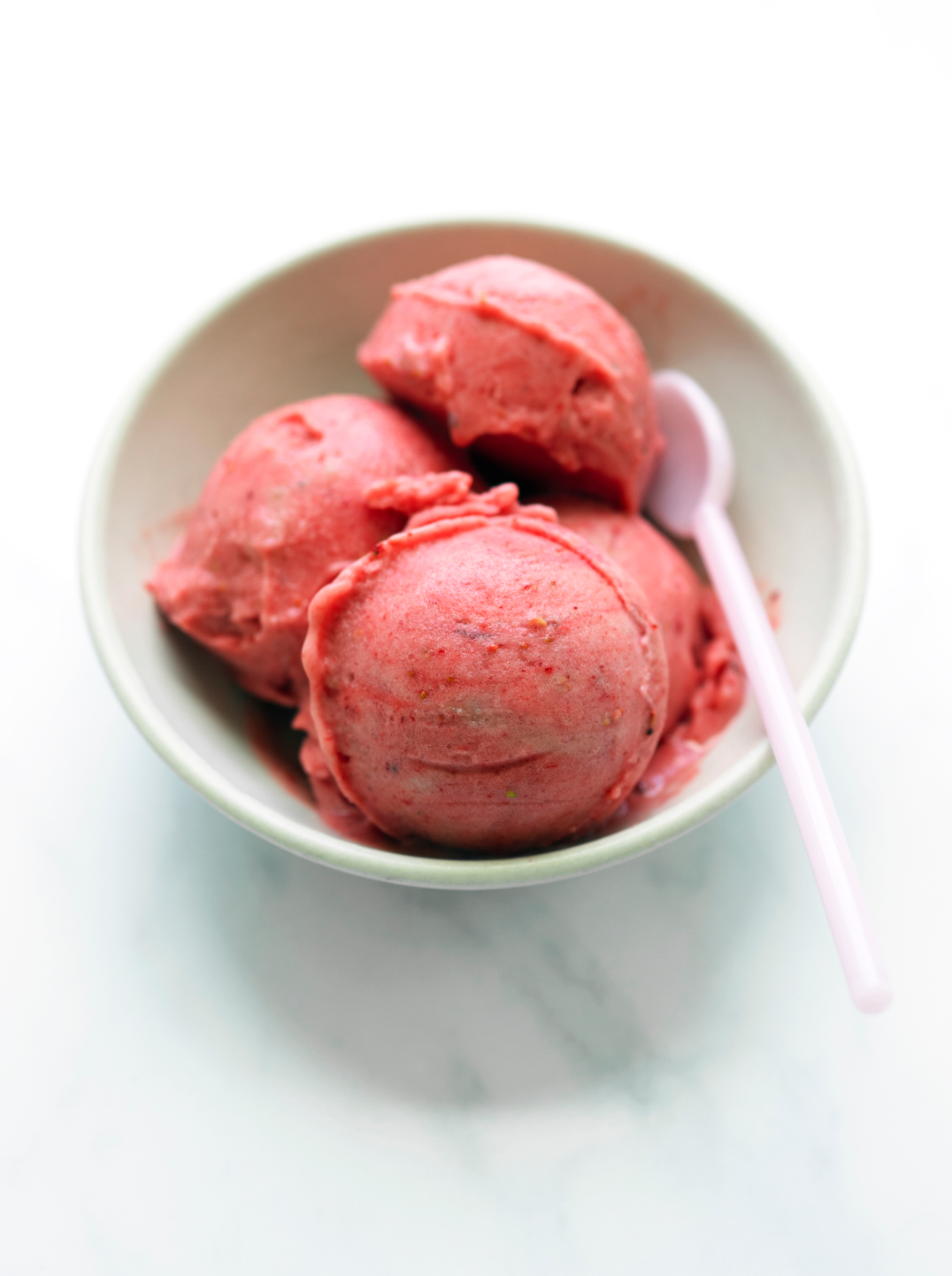 A white bowl with 3 scoops of Berry Banana Sorbet and a white spoon