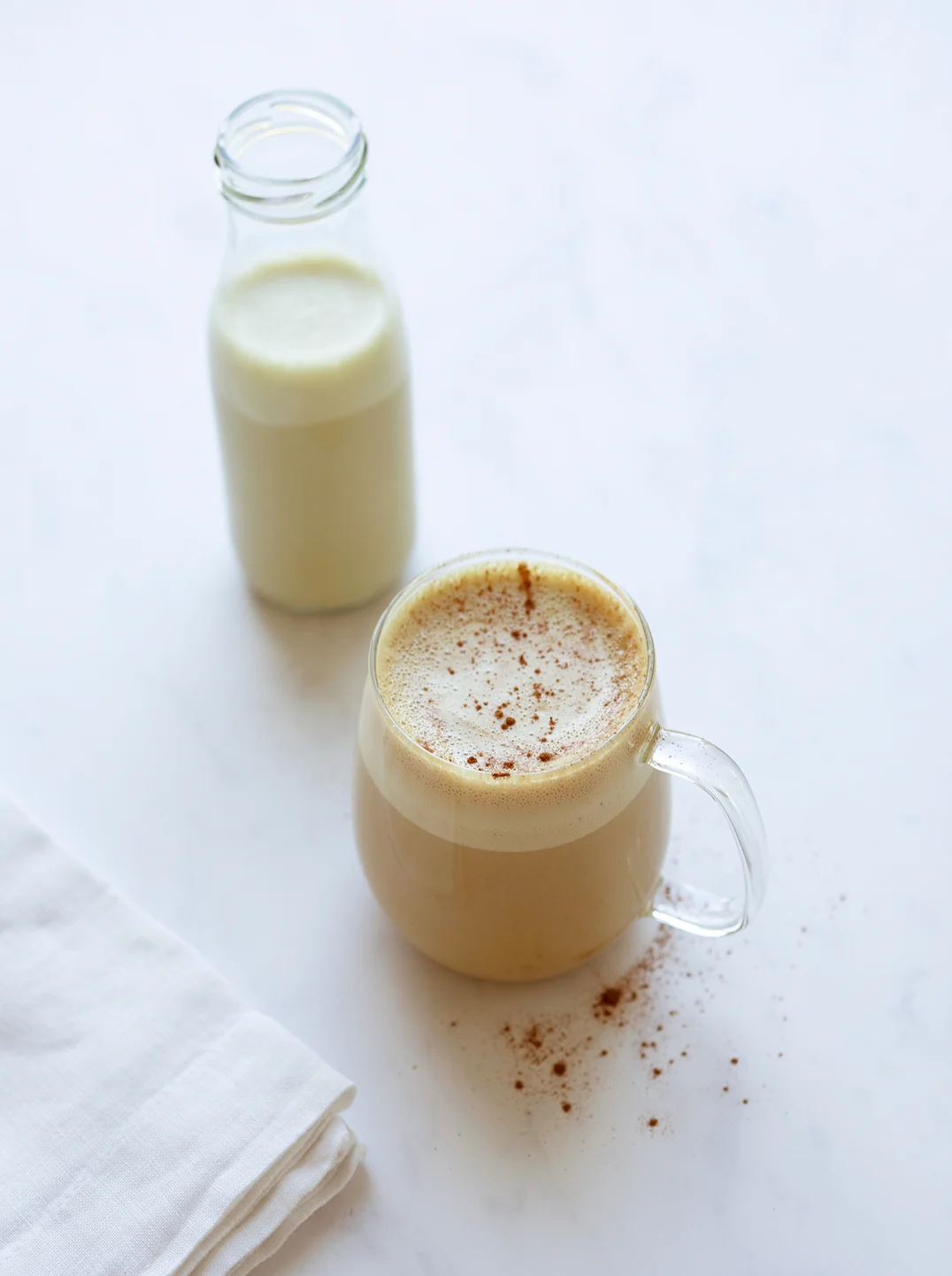 a glass and small bottle of maple pistachio milk