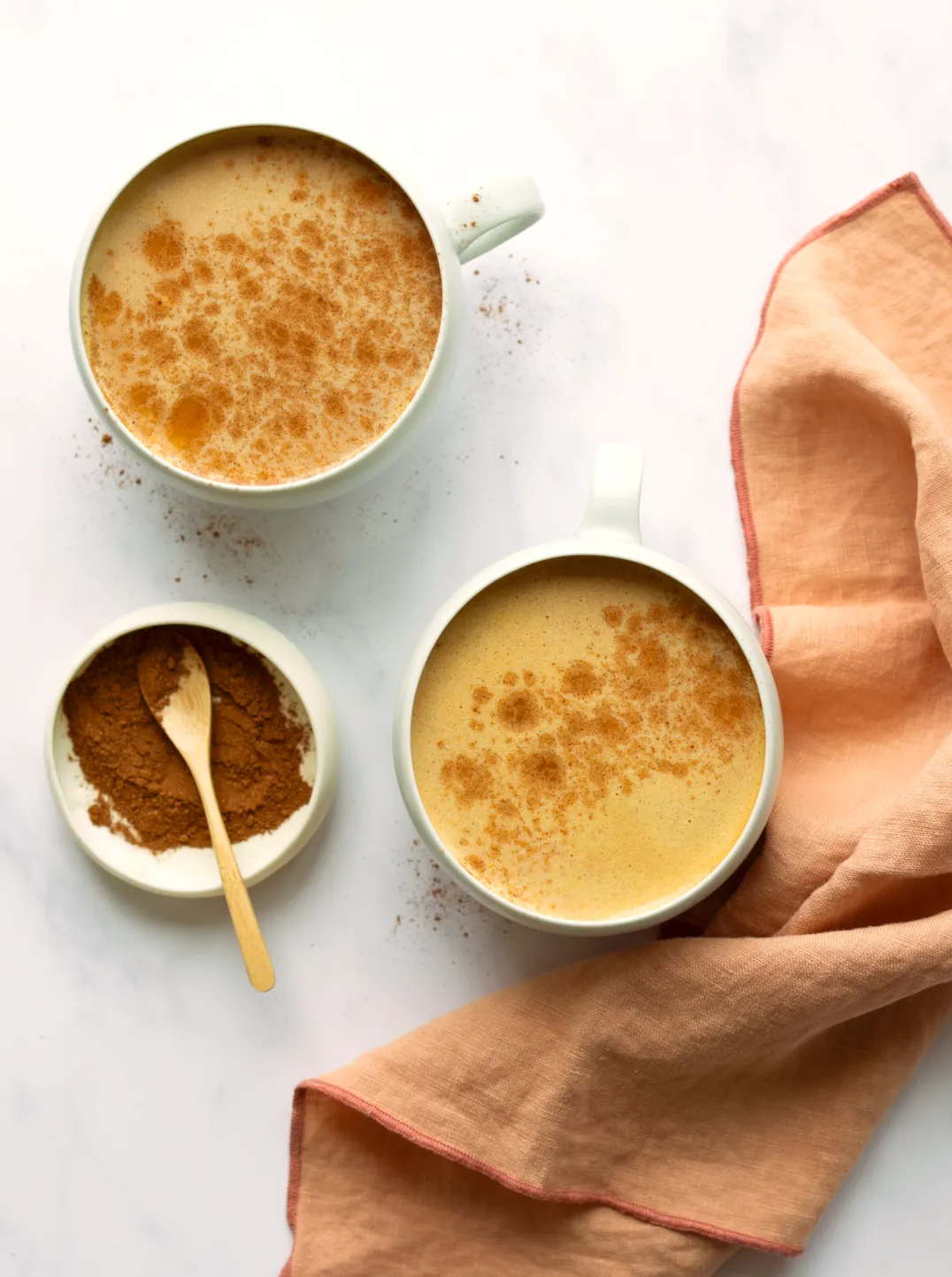 2 cups of pumpkin spice latte a napkin and small bowl of pumpkin pie spice