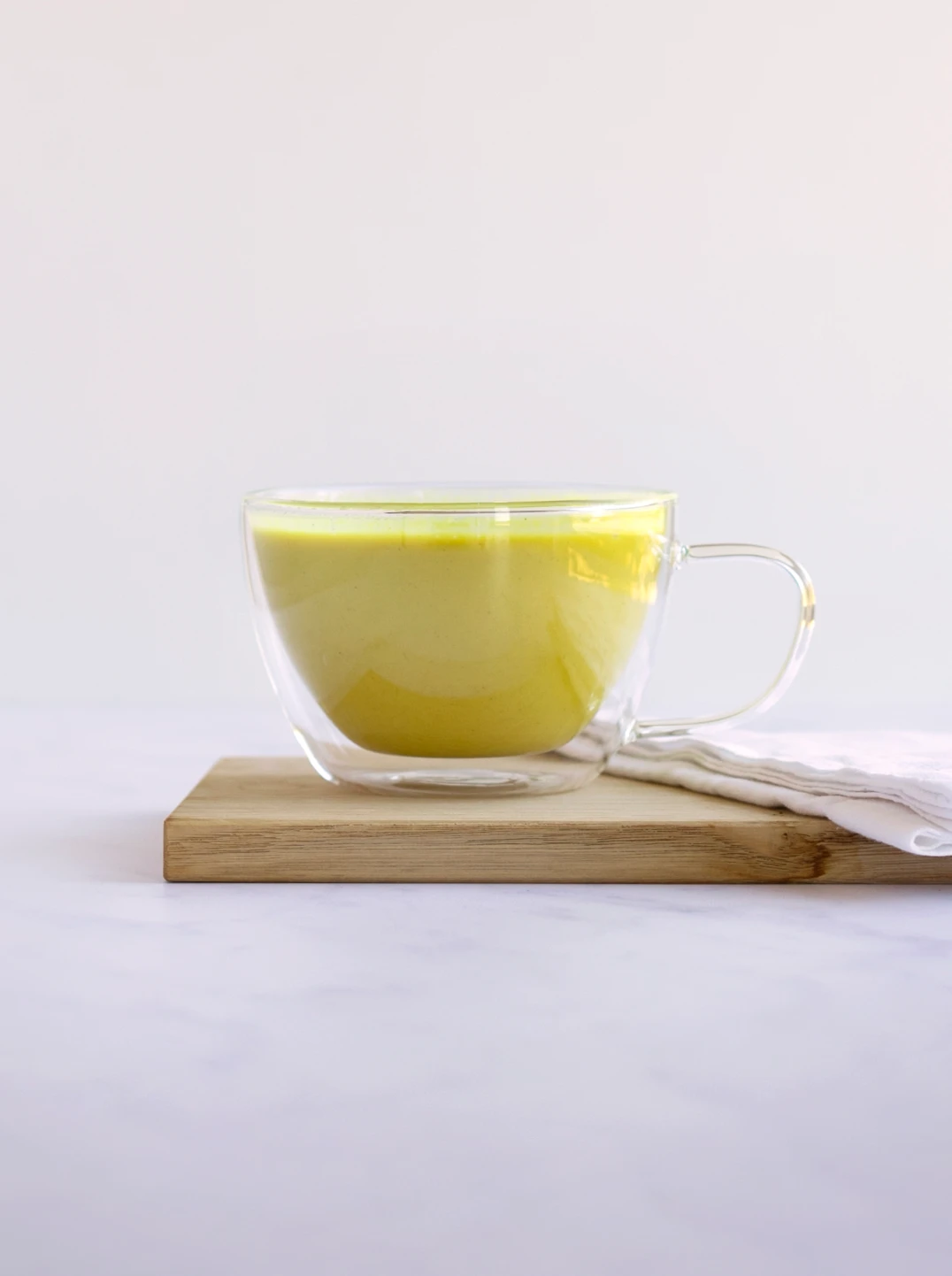 a glass tea cup filled with golden yellow chamomile moon milk