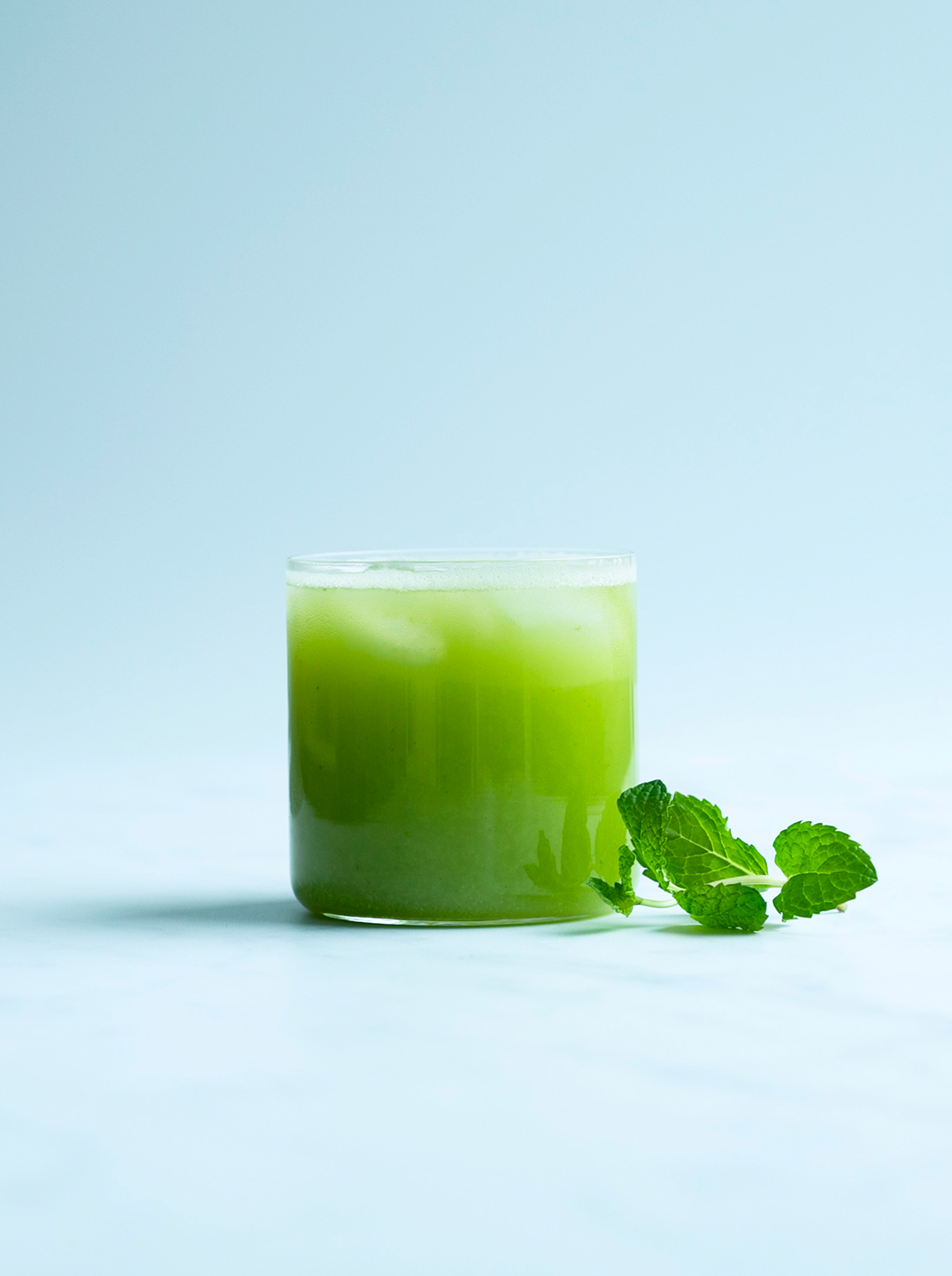 a glass of cool greens juice with a sprig of mint