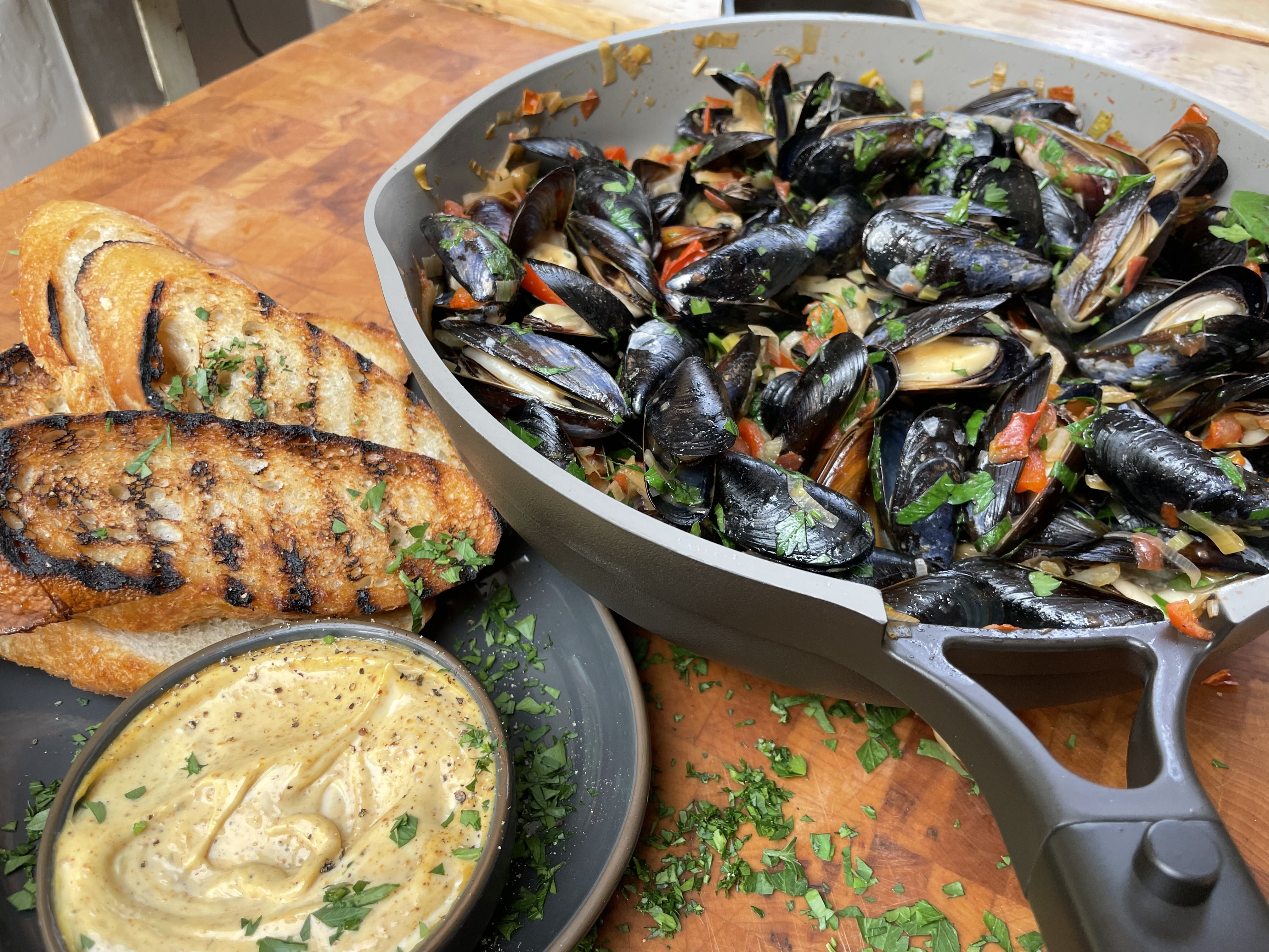 mussels in tomato stew cooking in always pan with grilled bread