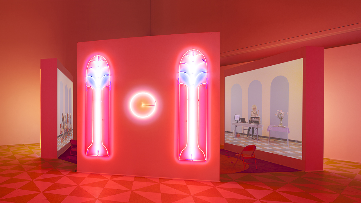 Alex Da Corte (b. 1980) and Jayson Musson (b. 1977), Easternsports, 2014. Four-channel video, color, sound; 152 min., with four screens, neon, carpet, vinyl composition tile, metal folding chairs, artificial oranges, orange scent, and diffusers. Score by Devonté Hynes. Collection of the artists; courtesy David Risley Gallery, Copenhagen, and Salon 94, New York. Installation view, Institute of Contemporary Art, University of Pennsylvania, 2014 © Alex Da Corte; image courtesy the artist and Institute of Contemporary Art, University of Pennsylvania

Hito
