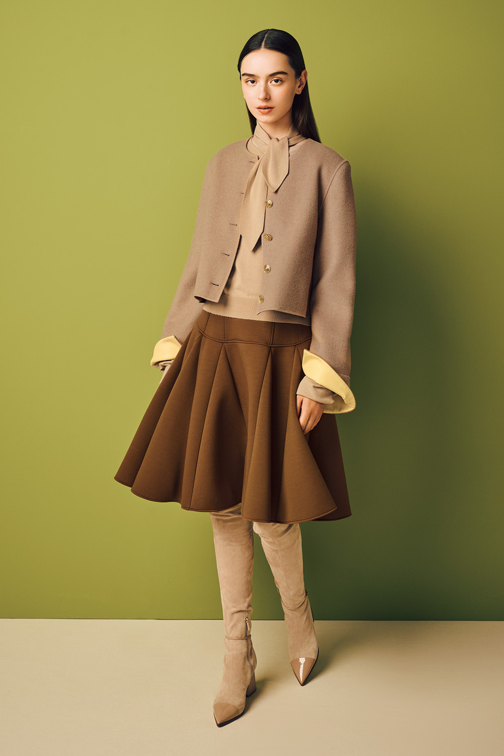 Model is wearing a brown skirt and a beige jacket on a light beige sweater.