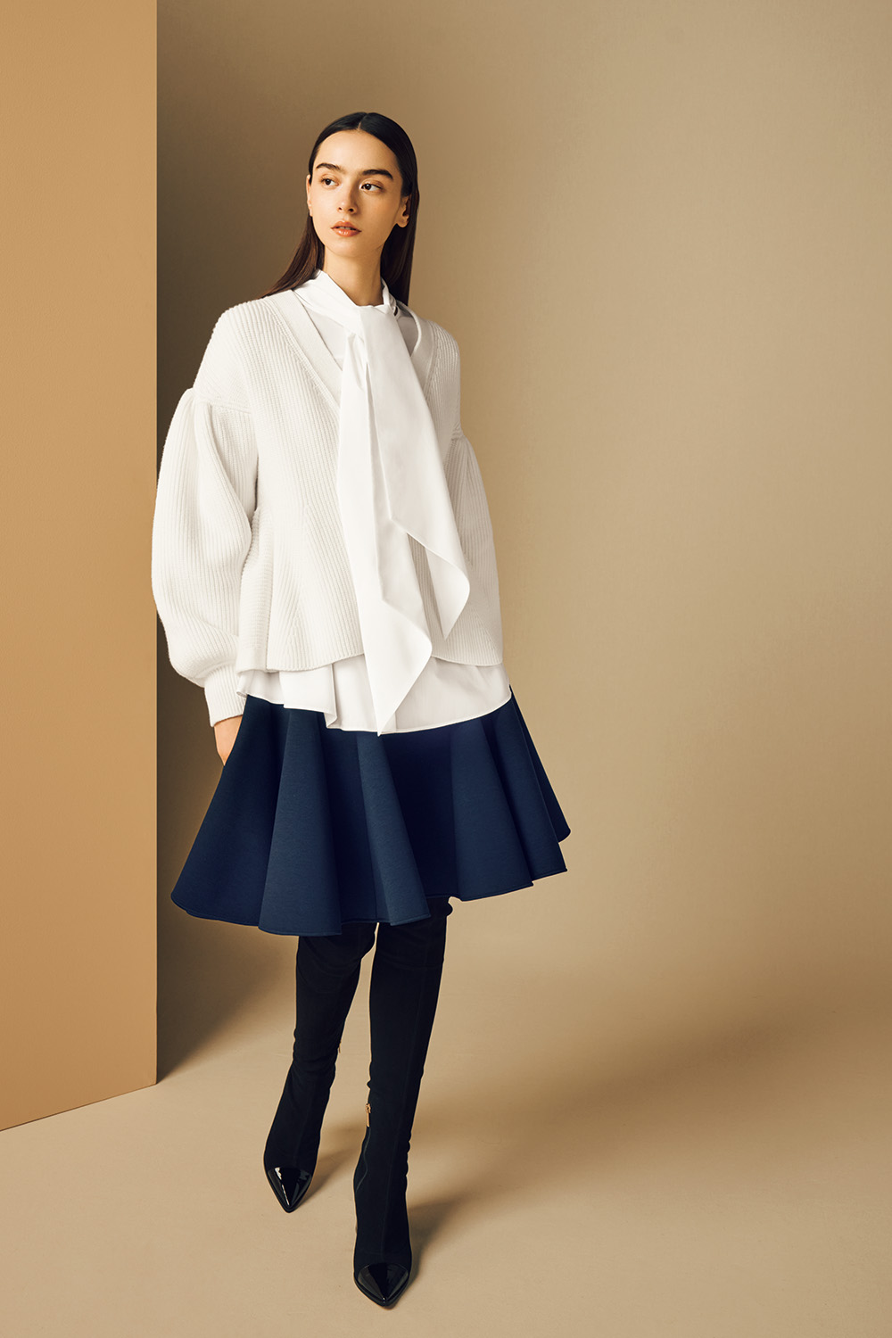 Model is wearing a white shirt and a deep blue skirt.