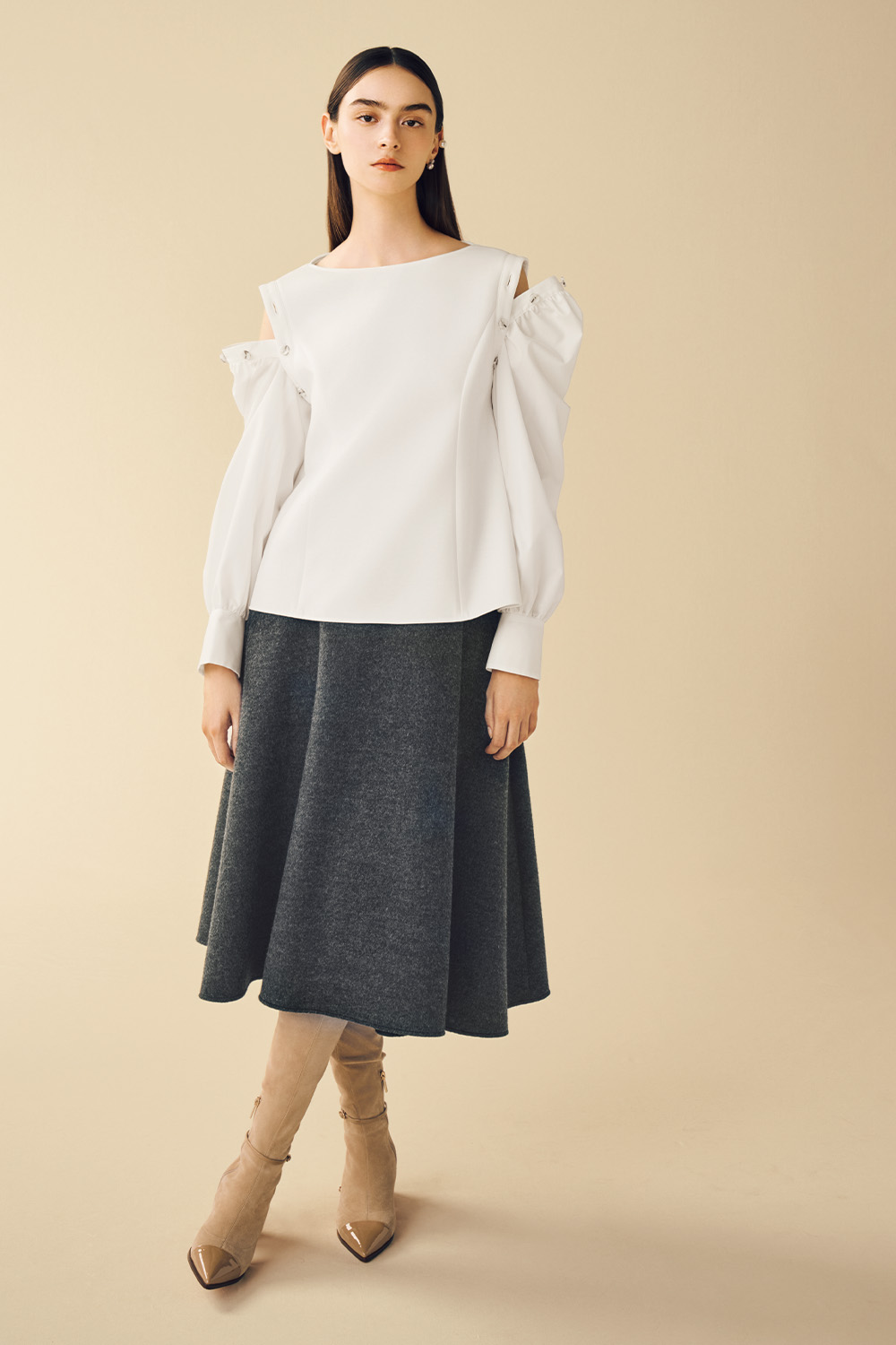 Model is wearing a white top paired with a stylish gray skirt.