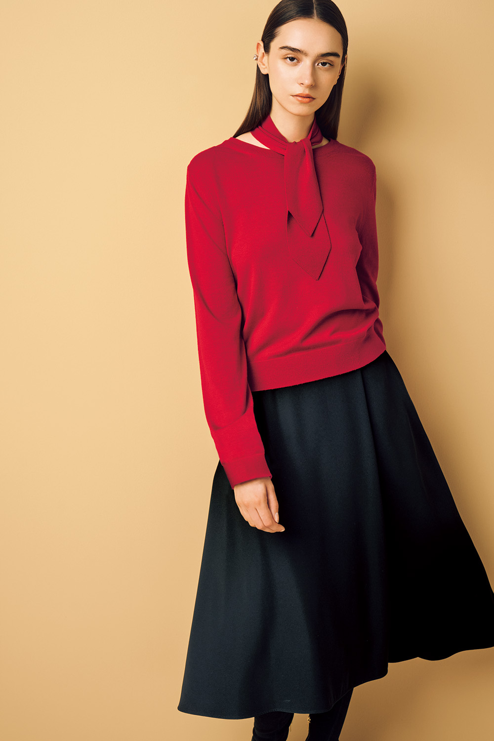 Model is wearing a red knit top and a black skirt.