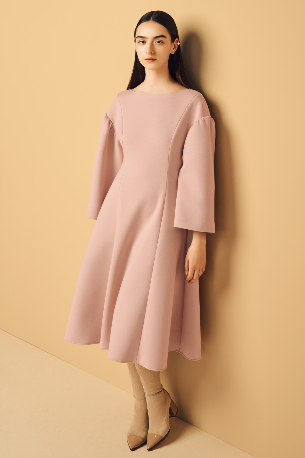 Model is wearing a pink dress and black long boots