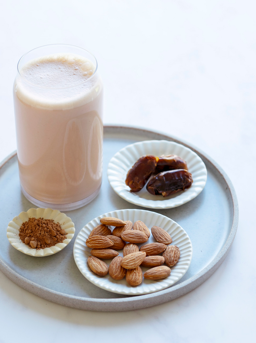 a glass of chocolate almond milk with ingredients on a tray