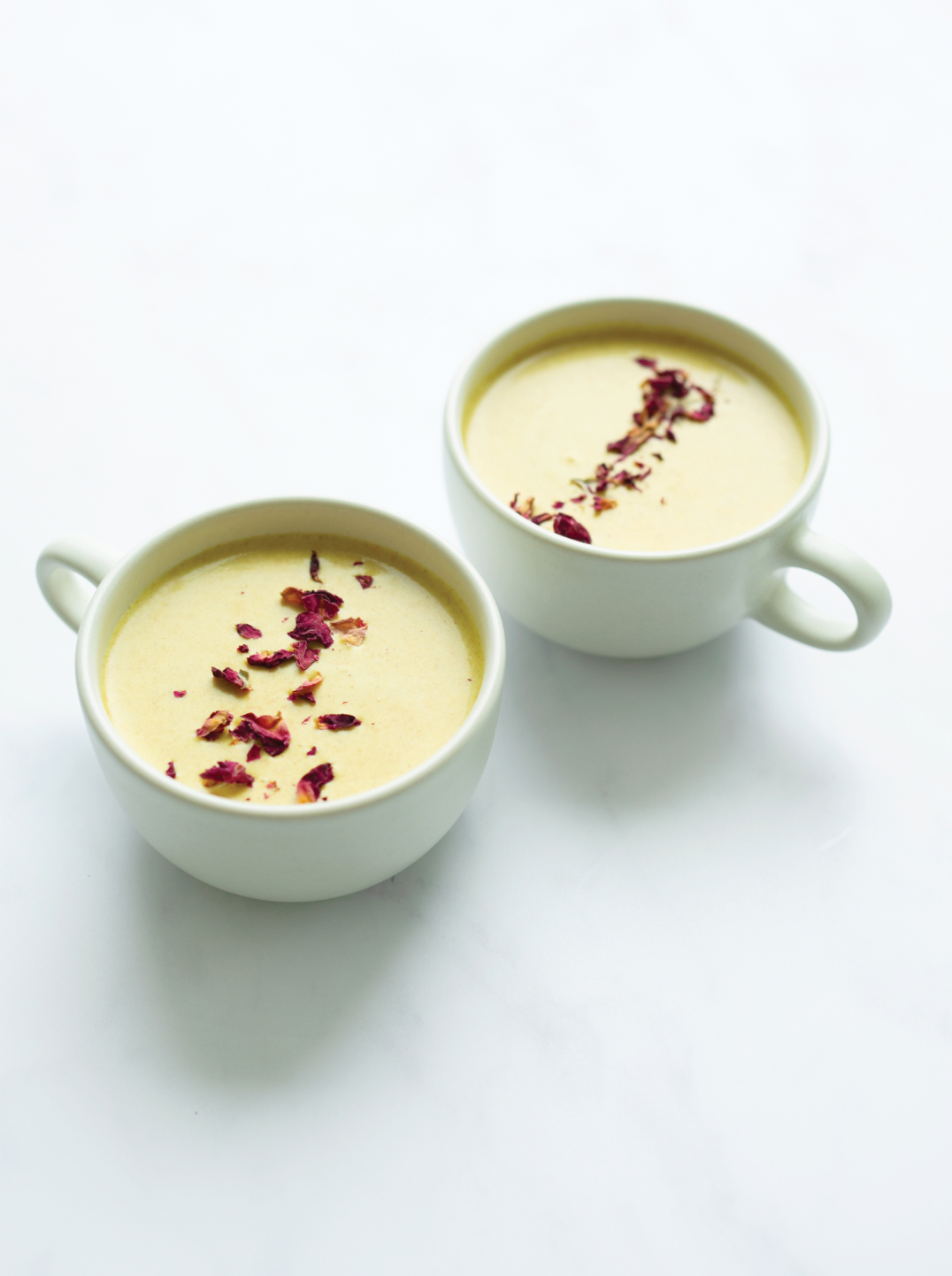 Two large cups filled with Golden Milk and garnished with spices