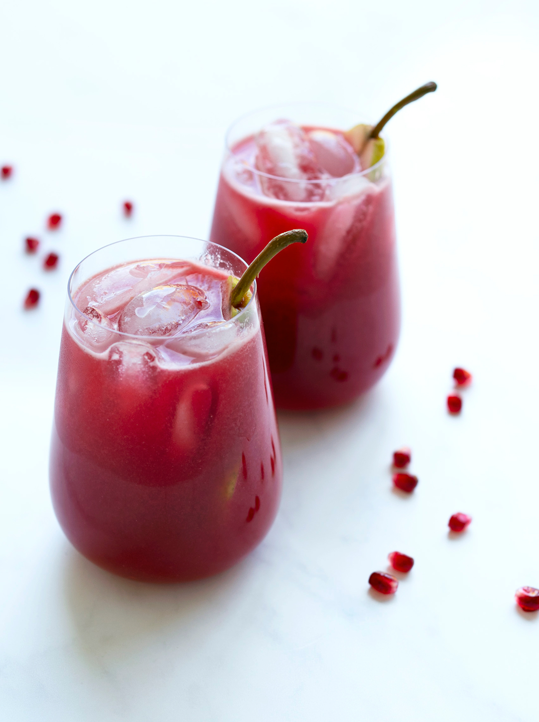 2 glasses of red crimson pear juice on ice with straws